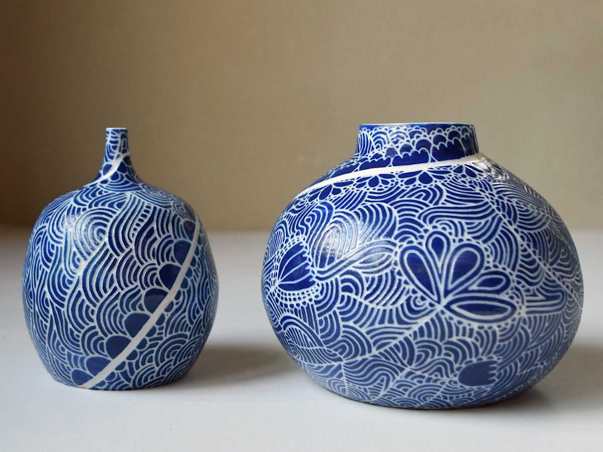 Two blue ceramic vases with intricate patterns on a beige background