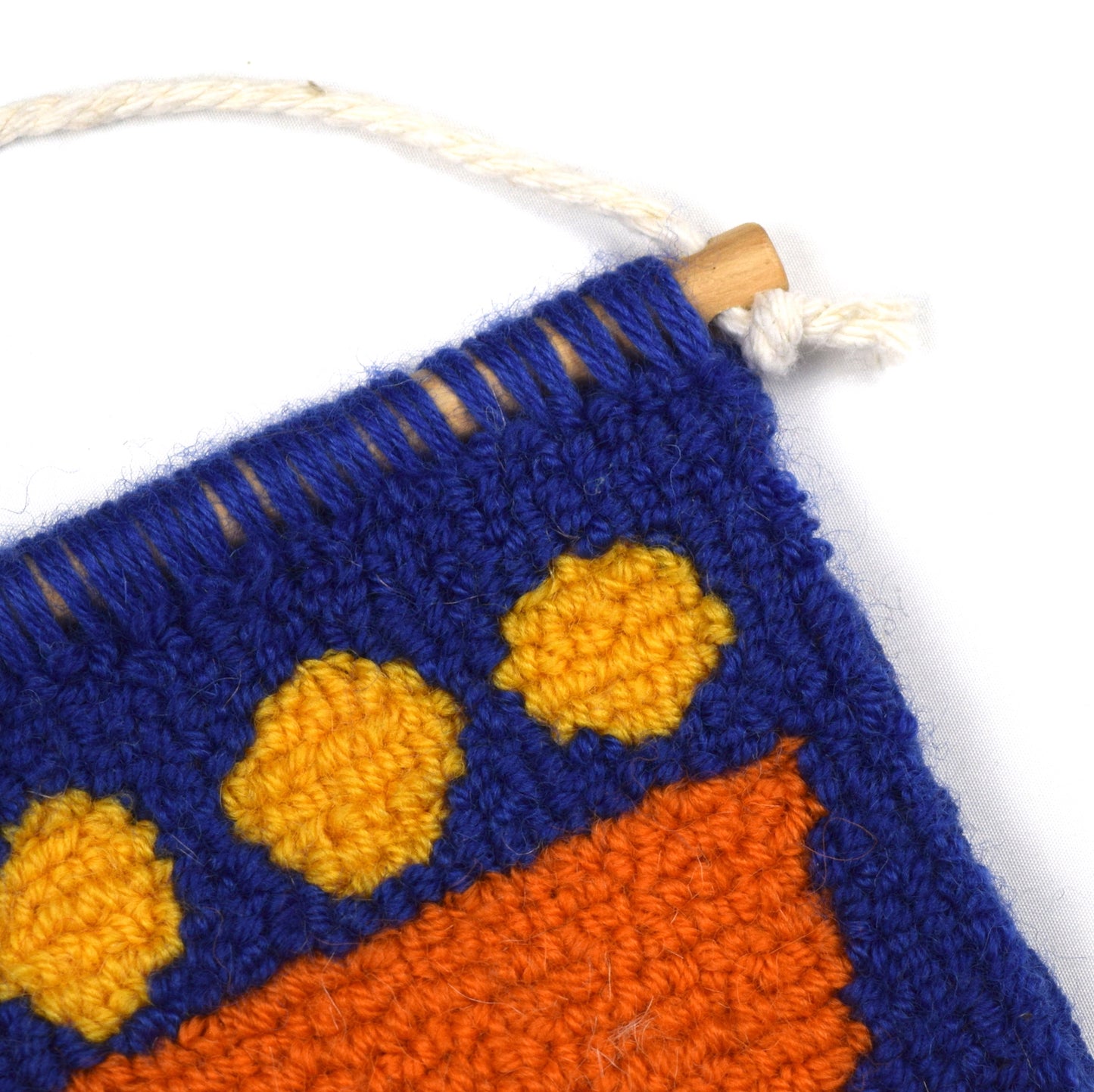 A contemporary hand punched miniature made using British Wool in royal blue, an orange semi-circle and yellow circles close up.