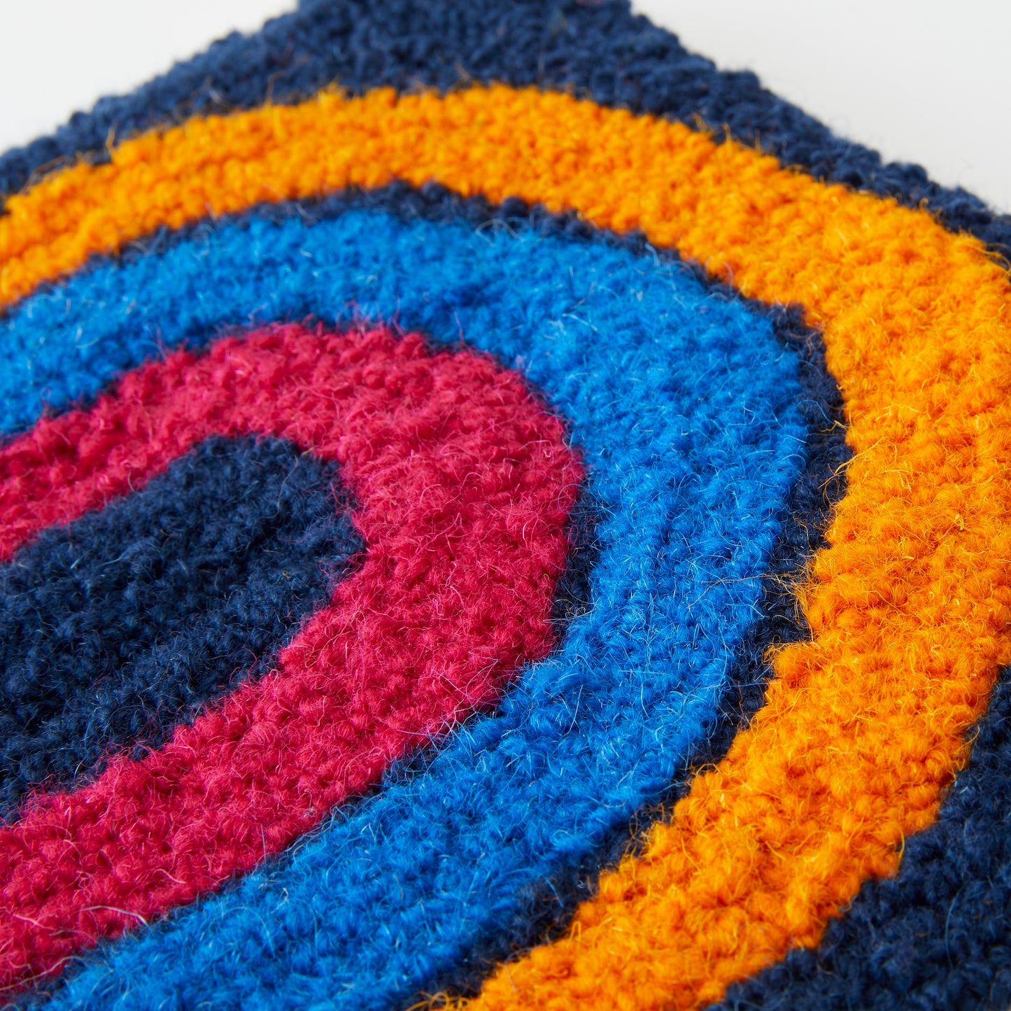 A loop pile tufted wall hanging in navy, orange, royal blue and magenta. This rainbow design has playful ‘illustrated’ edges close up.