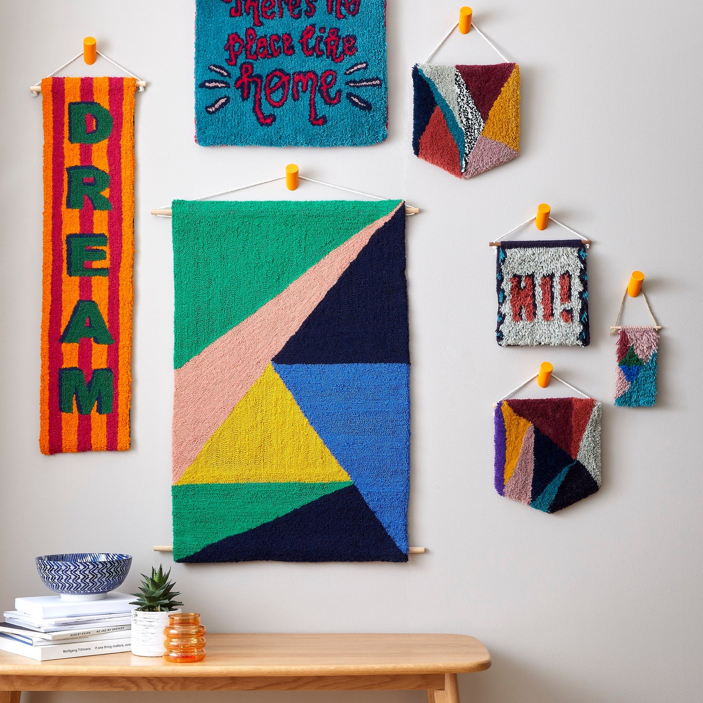 A harmonious collection of block colours (green, salmon, navy, royal blue and mustard). Arranged in a contemporary triangular design. Each pop of colour balanced perfectly with the rest of the design, this hand tufted wall hanging, a combination of both bold and calming colours as a part of a group image.