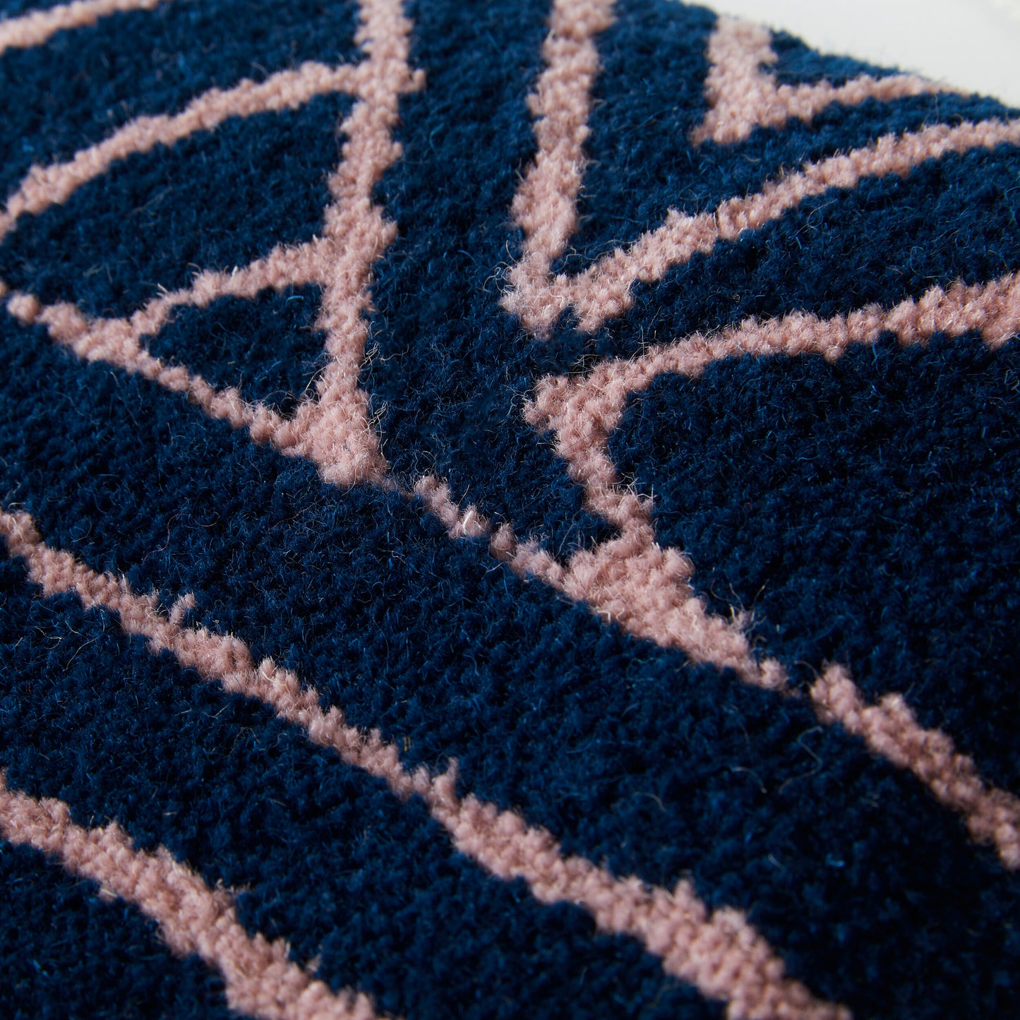 Navy cut pile wall hanging with lilac accents in a contemporary triangular design. Made using reclaimed yarns close up.