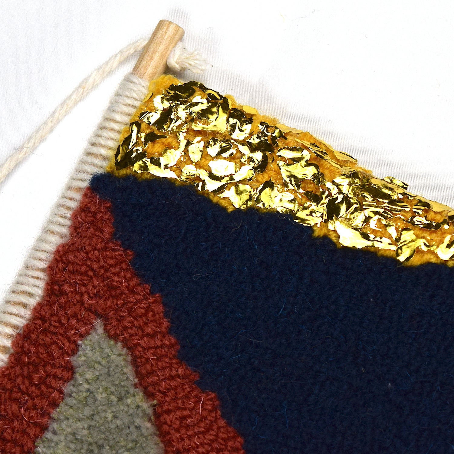 A fun mixture of FRAGMENT triangular shaped pieces created using British Wool and Reclaimed Yarns in a mixture of loop and cut piles and glorious gold accents. Coral, Khaki, Green, Navy and Yellow with a Black and White stripe close up.