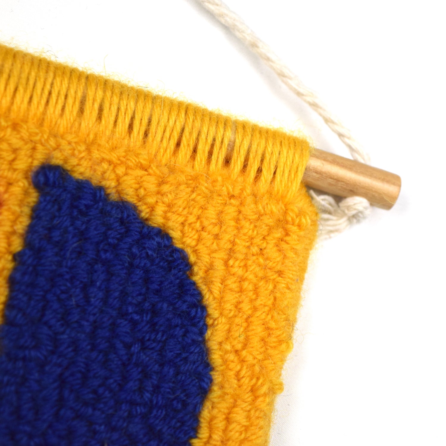 A contemporary hand punched miniature Wall Hanging, in bright yellow, royal blue and coral accents. Using simple shapes and colour. Using British Wool close up.