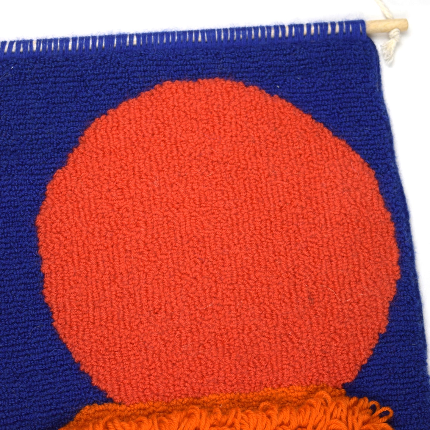 Using a simple circle and oblong shapes to create a contemporary sunset, hand punched using British Wool with a royal blue background, Coral circle, Orange, Yellow and Cream oblongs, with long loops in the centre close up. 