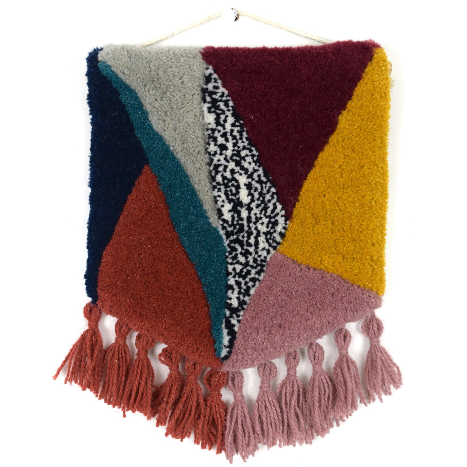 Triangular blocks of colour, the cut pile tuft carved in to pillowy shapes mixing complementary and contrasting Maroon, Coral, Khaki, Navy, Turquoise, Lilac, Mustard, dotted Black and White Reclaimed Yarn, with Coral and Lilac tassels.