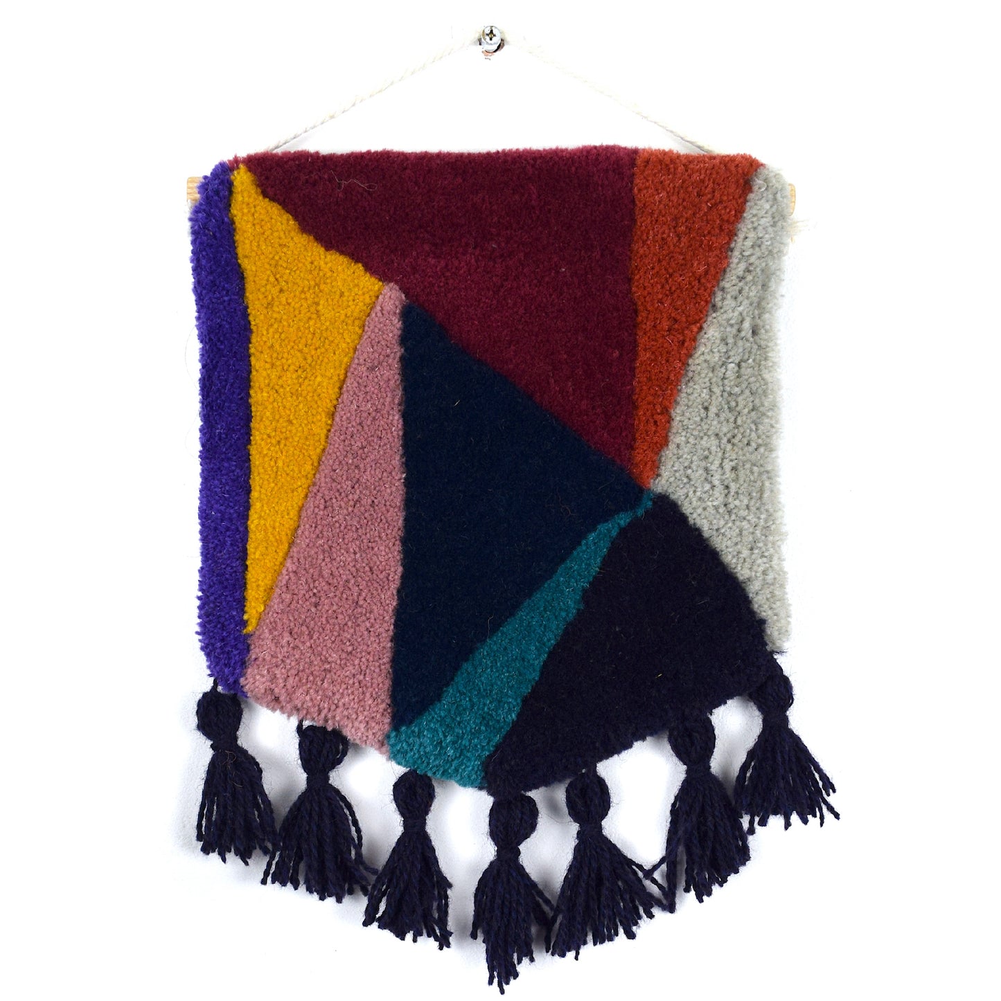 Triangular blocks of colour, the cut pile tuft carved in to pillowy shapes mixing complementary and contrasting Maroon, Coral, Khaki, Aubergine, Turquoise, Navy, Lilac, Mustard and Purple Reclaimed Yarn, with Aubergine tassels.