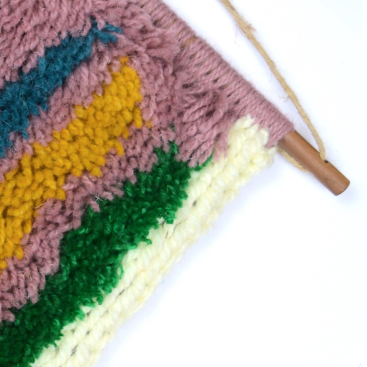 A contemporary hand latch hooked wall hanging, using a mixture of textures, latch hook, locker hook and punch needle with simple shapes and colour (lilac, aubergine, cream, blue, turquoise, mustard and green), showcasing Reclaimed Yarn and Yarn from previous projects. Close up.