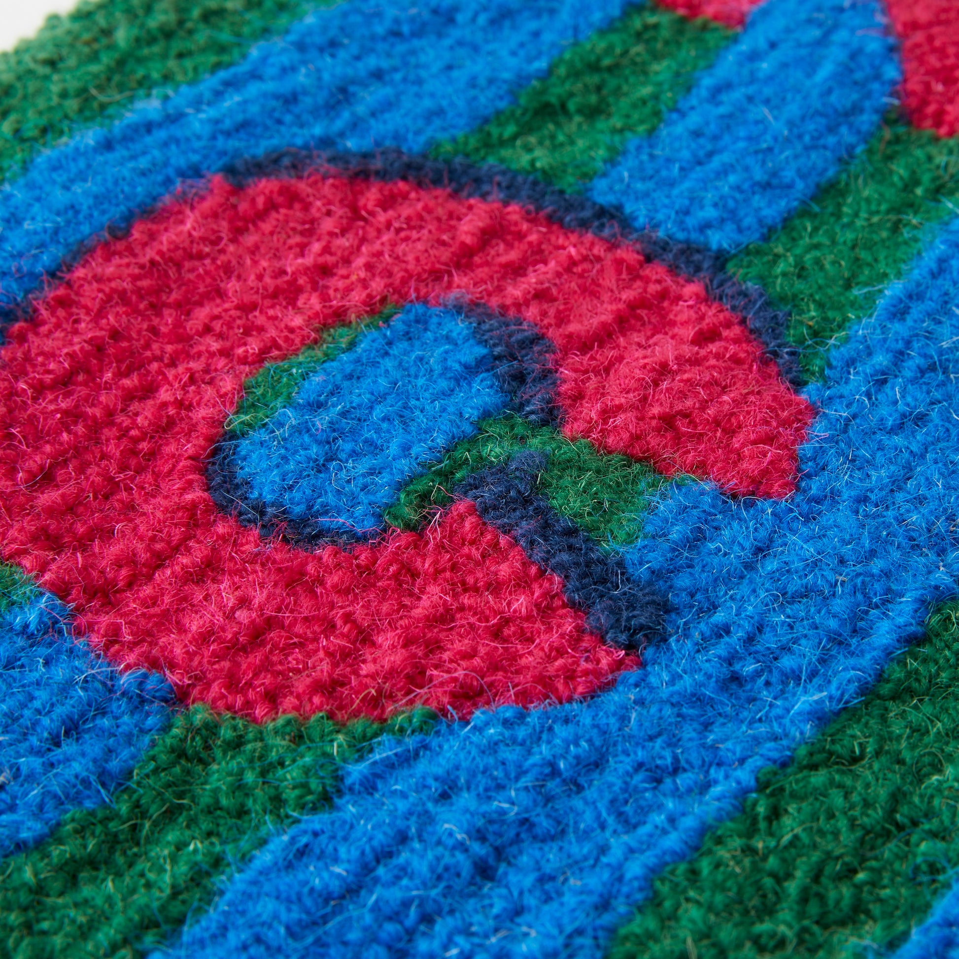 DANCE in a bold shadow text in Magenta, Navy and Bright Blue and Green Stripe background in a loop pile using reclaimed yarn close up.