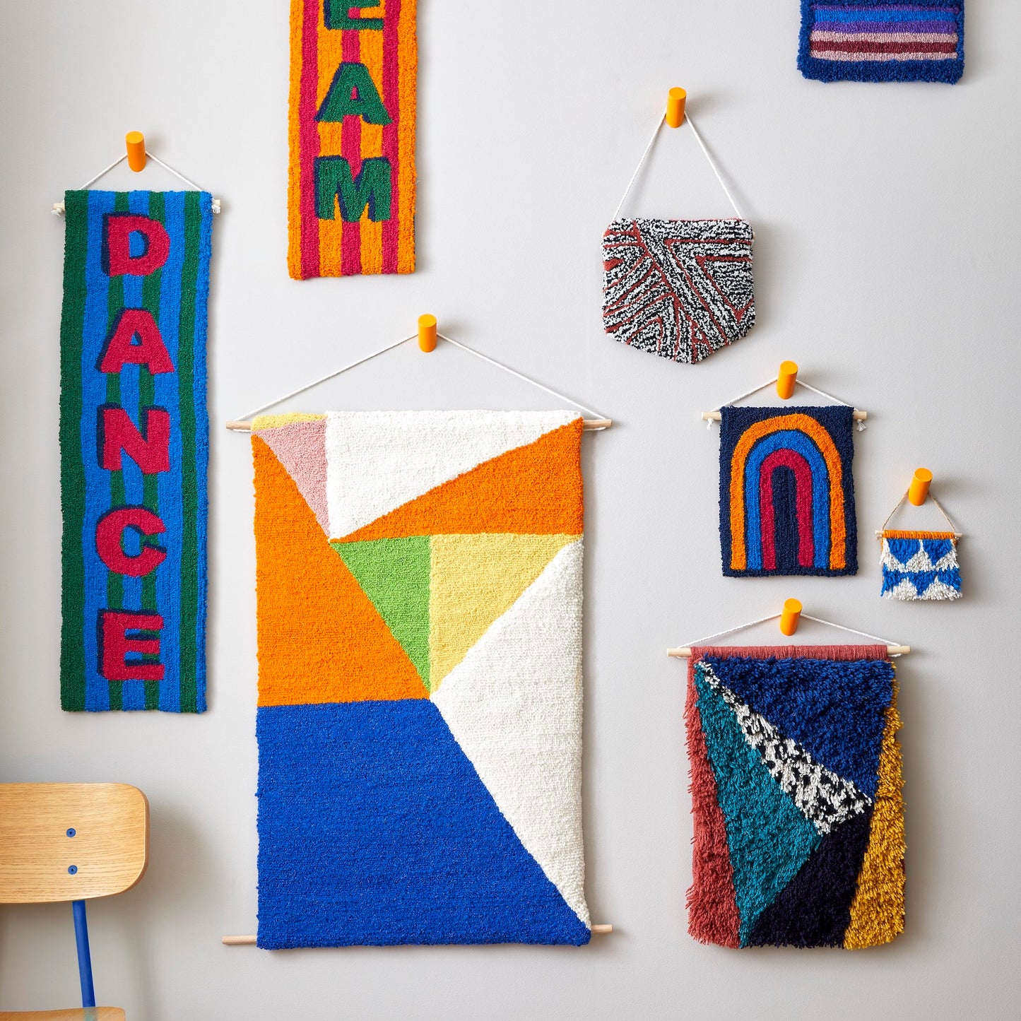 A loop pile tufted wall hanging in navy, orange, royal blue and magenta. This rainbow design has playful ‘illustrated’ edges as a part of a group image.
